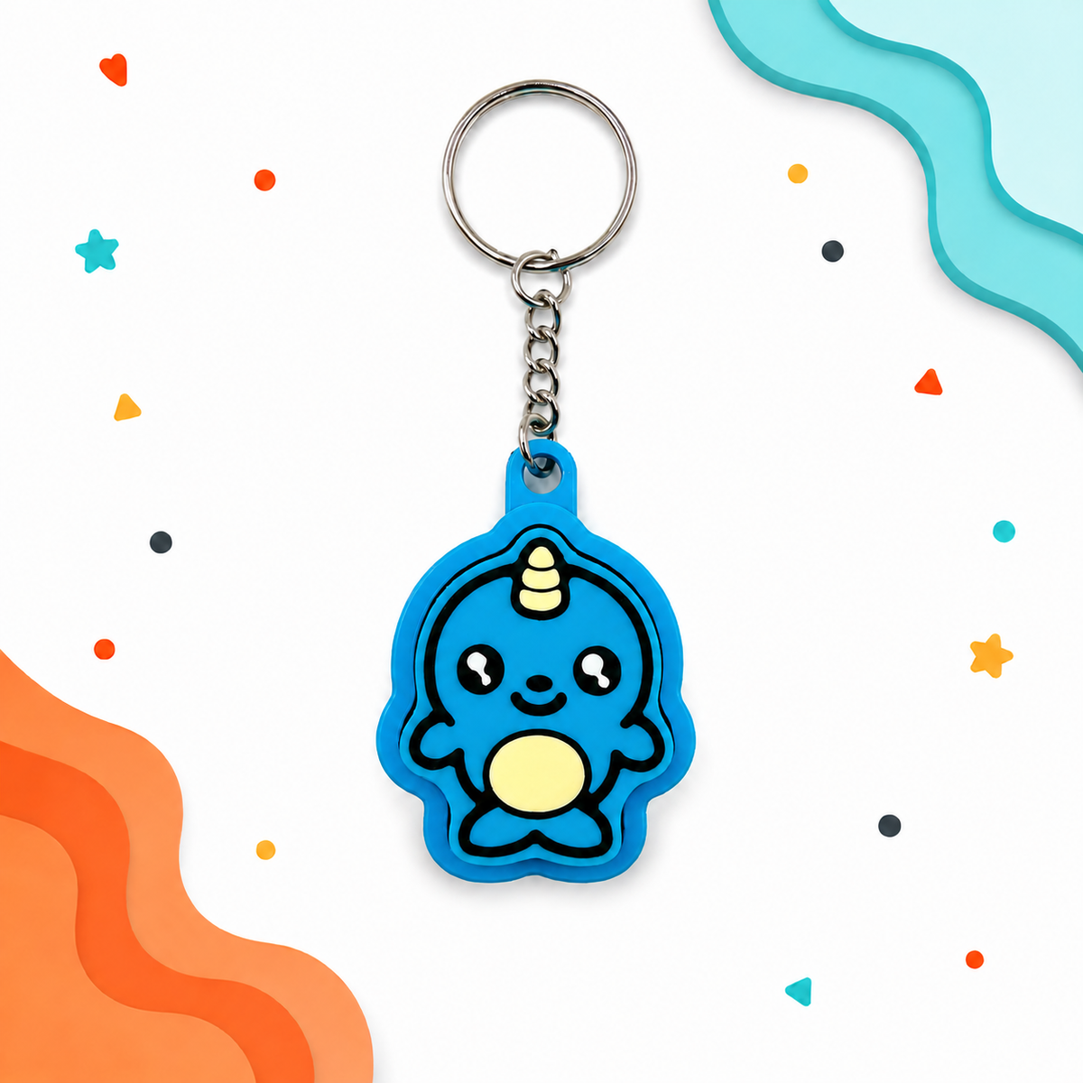 Blue narwhal clicker keychain displayed on a white background with layered aqua and orange corner shapes and colorful playful accents.