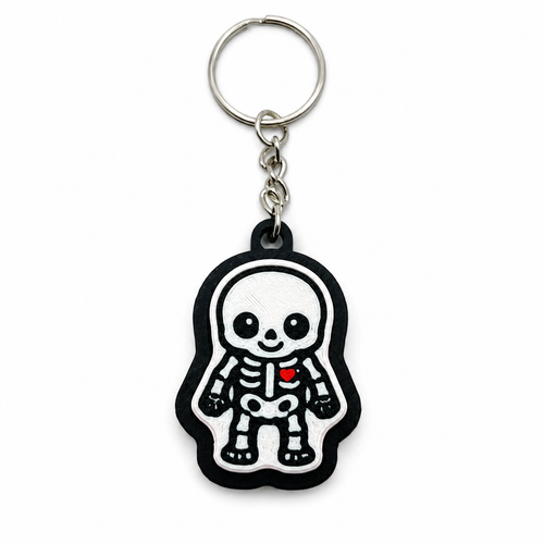 Front view of a black and white 3D-printed skeleton fidget clicker keychain with a small red heart and metal keyring.