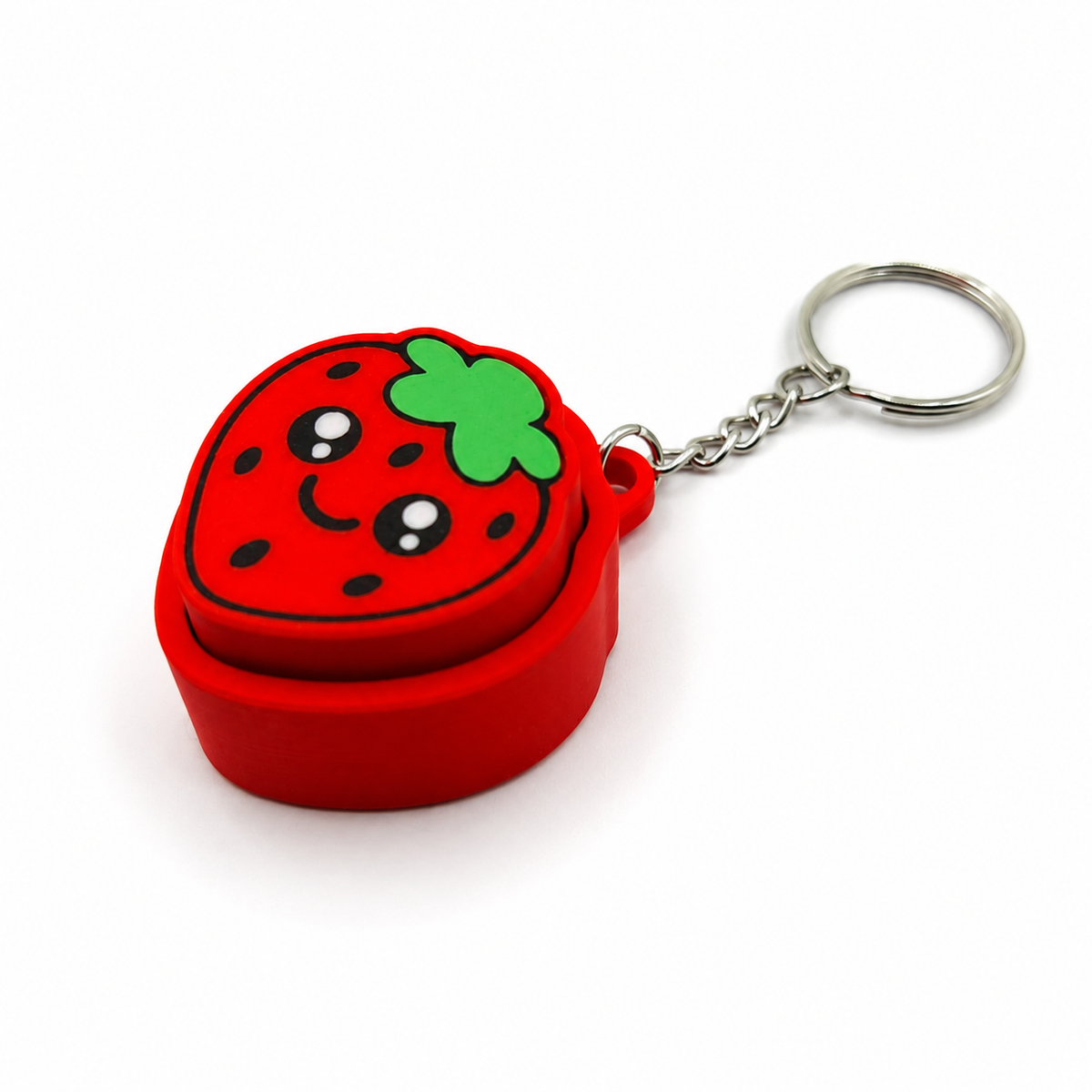 Angled view of a red strawberry clicker keychain showing the raised pressable berry top, green leaves, black seed details, and silver keyring.